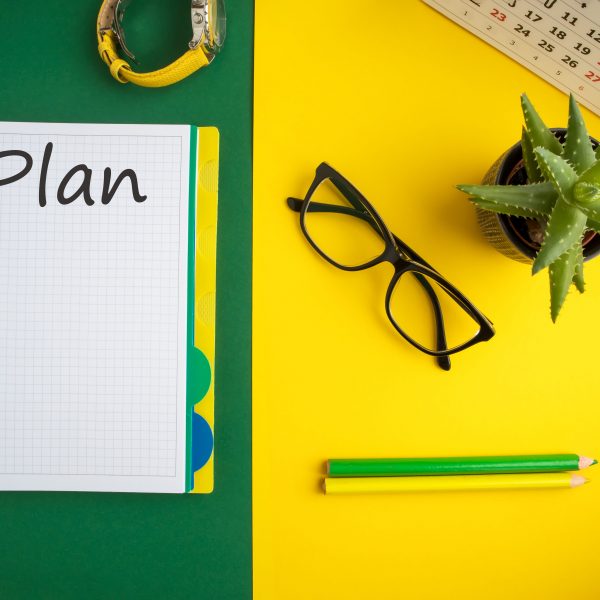 Notitieboekje, pennen, kalender en bril op een tafel