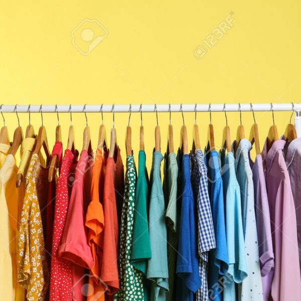 196544236 heldere kleren hangen op rek tegen gele achtergrond regenboog kleuren